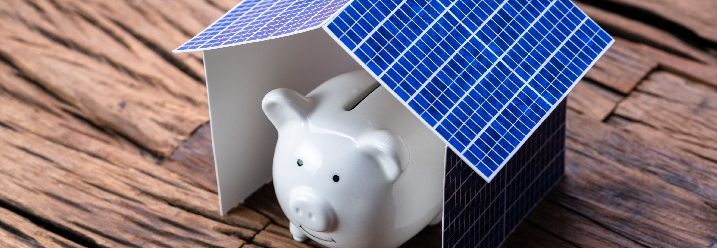 Sparschwein unter gebasteltem Haus aus Solarpanelen